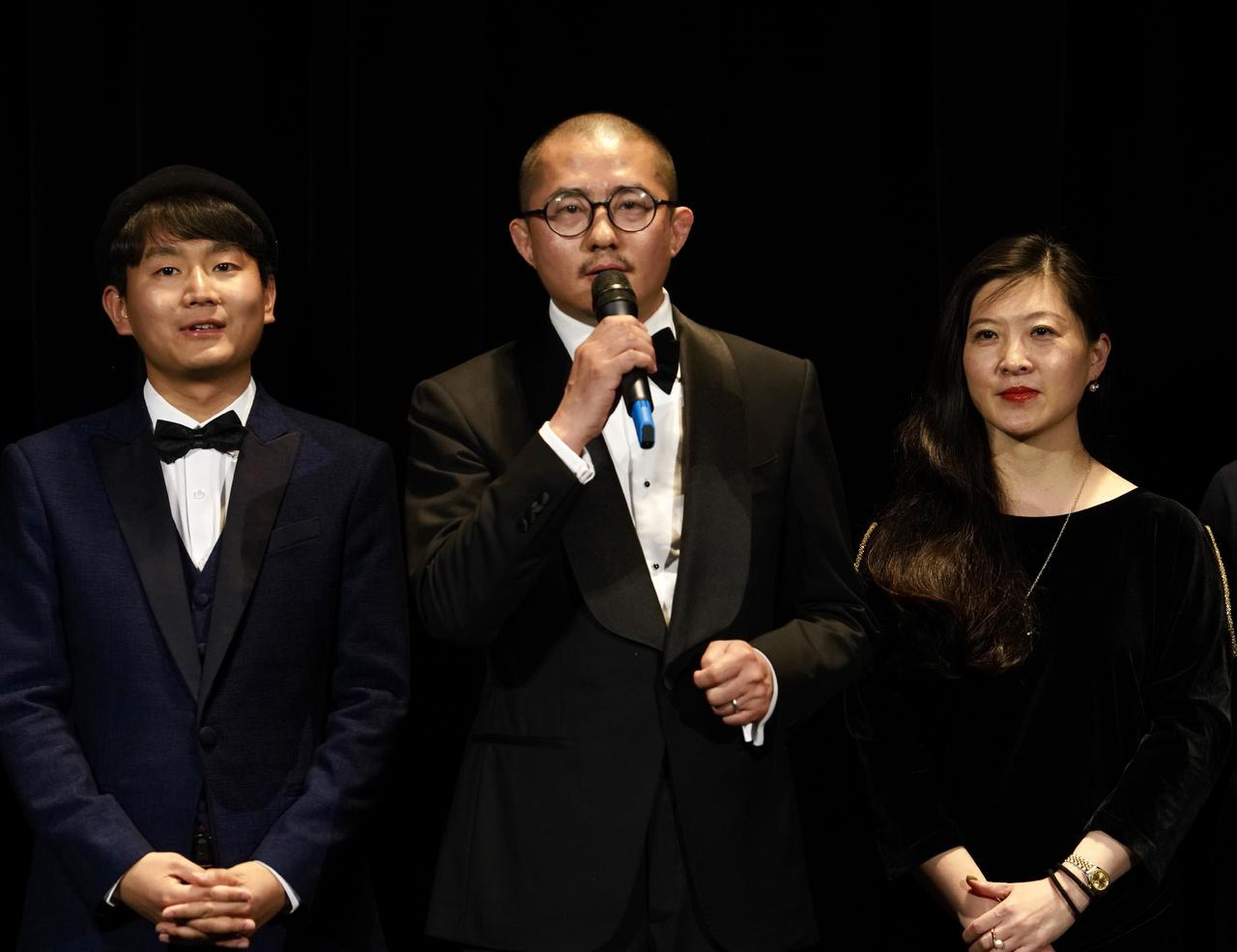 出品人、总制片人、工厂大门影业CEO：黄旭峰在首映礼上致辞，左为导演顾晓刚，右为总制片人，大地电影总经理：张群